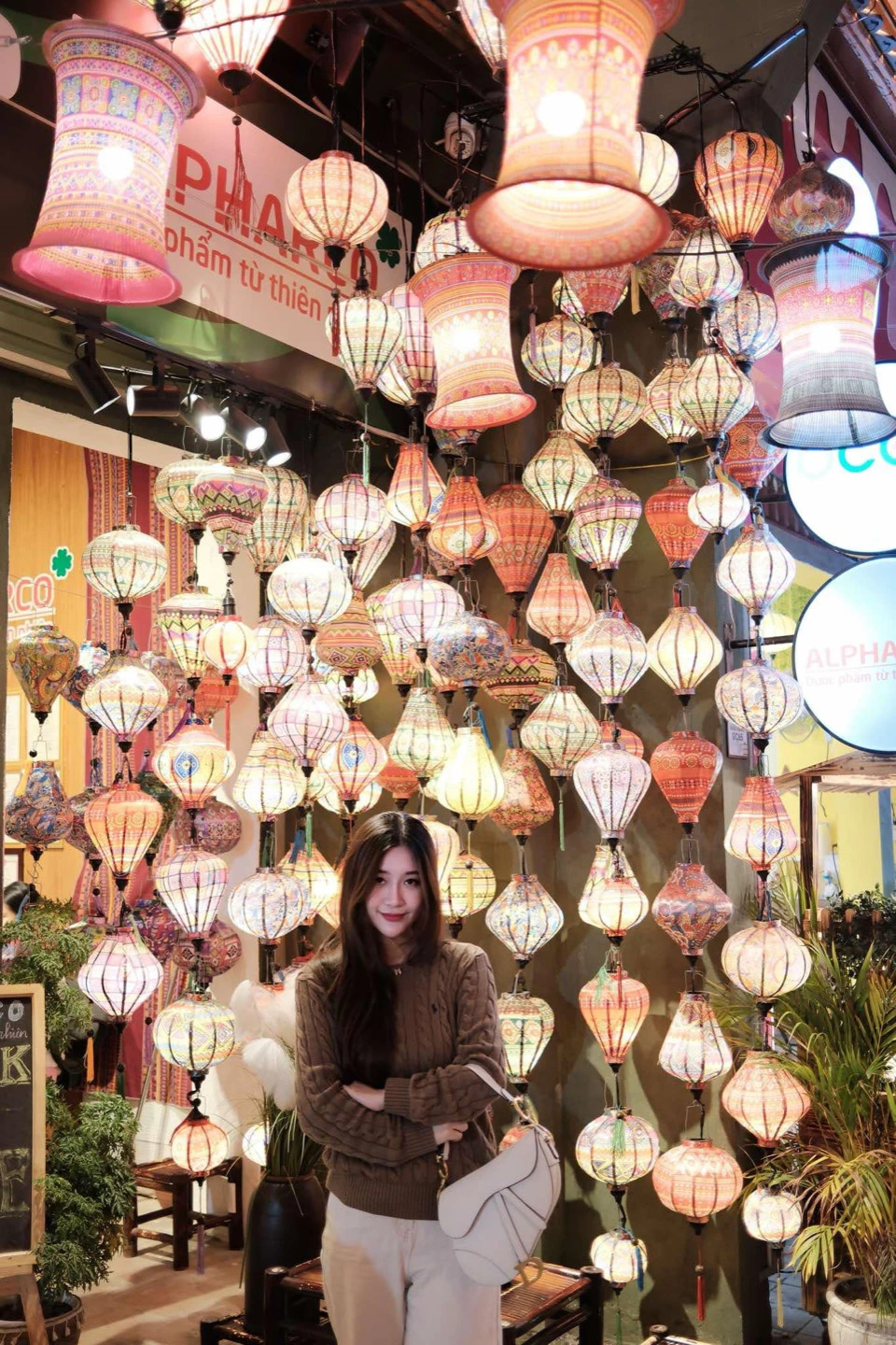 A woman standing beneath a large display of glowing lanterns.